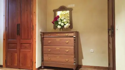 a dresser with a mirror and a vase of flowers on top at Casa rural Puchero y Manta in Alcudia de Veo
