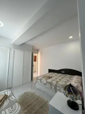 a white bedroom with a bed and a table at precioso apartamento a 10 metros de la playa in Cullera