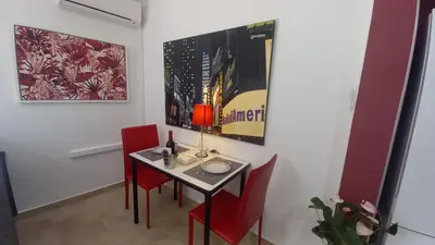 a dining room with a table and red chairs at El estudio de las mariposas,sofa cama , cocina y baño in Partida de La Cañada