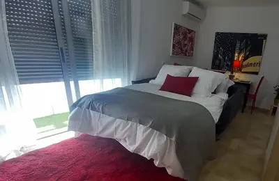 a bedroom with a bed with a red pillow on it at El estudio de las mariposas,sofa cama , cocina y baño in Partida de La Cañada
