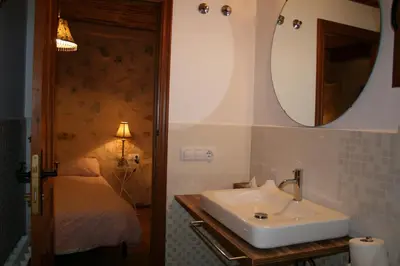 a bathroom with a sink and a mirror and a bed at La Casita de Las Estrellas in Algimia de Almonacid