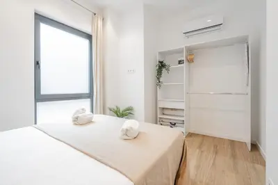 a white bedroom with a bed and a window at Mediterraneum Apto E in Valencia