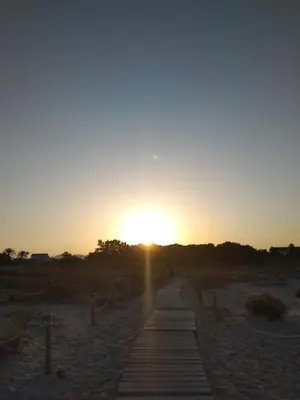 a sunset over a wooden path in the desert at Apartamento 2 habitaciones playa de Canet de Berenguer in Canet de Berenguer