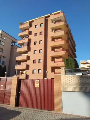 a tall building with a red fence next to it at Apartamento 2 habitaciones playa de Canet de Berenguer in Canet de Berenguer