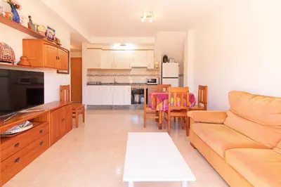 a living room and kitchen with a couch and a table at Global Vacacional, Apartamento con terraza de 70m y piscina en Canet de Berenguer in Canet de Berenguer
