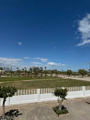 a white fence in front of a park with trees at La Costera in Barrio-Mar