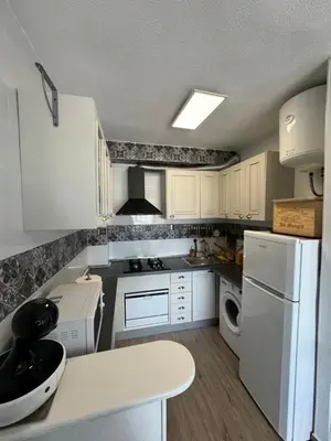 a kitchen with white cabinets and a white refrigerator at La Costera in Barrio-Mar
