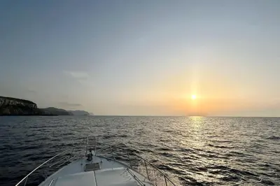 a boat in the water with the sun setting at Barco Apartamento Playa Valencia in Valencia