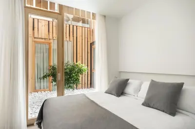 a white bedroom with a bed and a window at Apartamentos Maestro Sosa in Valencia