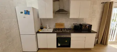 a kitchen with white cabinets and a refrigerator at Adosado playa Pobla Farnals in Puebla de Farnals