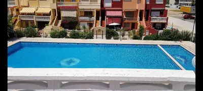 a large blue swimming pool in front of a building at Adosado playa Pobla Farnals in Puebla de Farnals