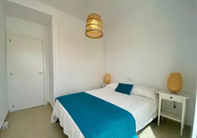 a bedroom with a blue and white bed and a lamp at Adosado en Playa Casablanca in Almenara