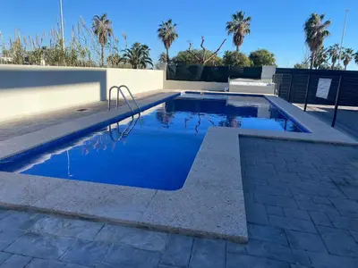 a swimming pool with blue water and palm trees at Adosado en Playa Casablanca in Almenara