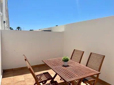 a wooden table with two chairs and a potted plant on it at Adosado en Playa Casablanca in Almenara