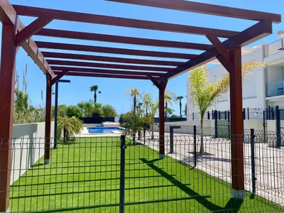 a wooden pergola in front of a building at Adosado en Playa Casablanca in Almenara