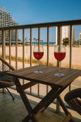 two glasses of red wine sitting on a wooden table on the beach at Cataleya Apartment in Cullera