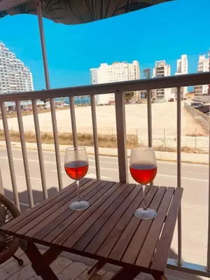 two glasses of wine sitting on a wooden table on a balcony at Cataleya Apartment in Cullera
