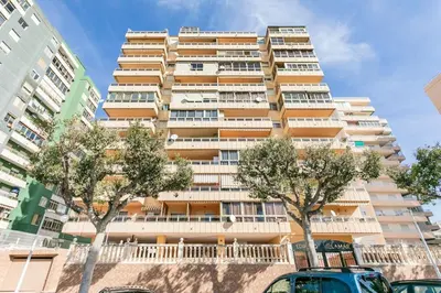 a tall building with trees in front of it at Villamar ,ACC, playa wifi y garaje in Cullera