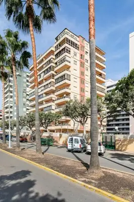 a city street with palm trees and a large building at Villamar ,ACC, playa wifi y garaje in Cullera