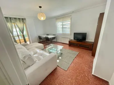a living room with a white couch and a table at Villamar ,ACC, playa wifi y garaje in Cullera