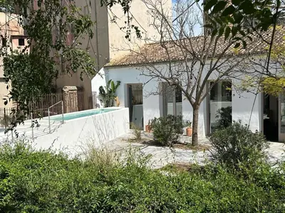 a white house with a tree and a swimming pool at Amazing suite by the fair in Valencia