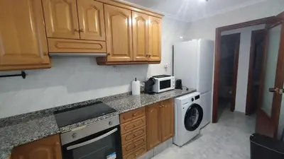 a kitchen with wooden cabinets and a white refrigerator at Sea view apartment, first line on the beach, Remote work in Canet de Berenguer