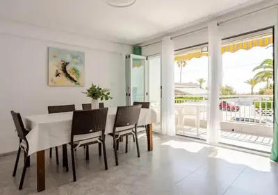a dining room with a table and chairs and a balcony at Sea view apartment, first line on the beach, Remote work in Canet de Berenguer