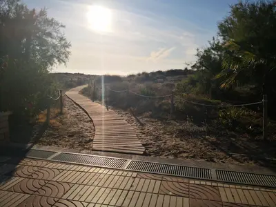 a walkway on a beach with the sun in the sky at Sea view apartment, first line on the beach, Remote work in Canet de Berenguer