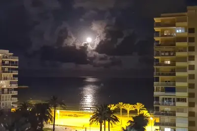 a moon in the sky over the ocean at night at Piso nuevo y con vistas in Cullera