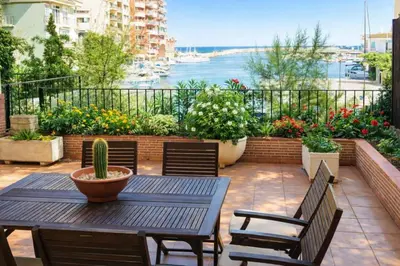 a patio with a table and chairs and flowers at Apartamento 1 linea mar terraza Port Saplaya in Port Saplaya