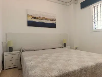 a bedroom with a bed and a painting on the wall at Apartamento 1 linea mar terraza Port Saplaya in Port Saplaya