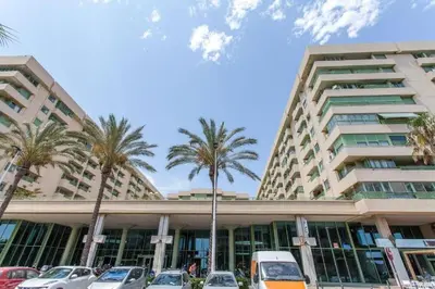 a large building with palm trees in front of it at Apartamento playa Patacona con parking in Valencia