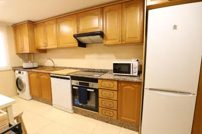 a kitchen with wooden cabinets and a white refrigerator at Maravilloso adosado para 8 en entorno privilegiado by Hometels in Canet de Berenguer