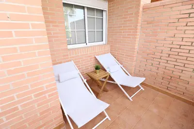 two white chairs and a table on a brick wall at Maravilloso adosado para 8 en entorno privilegiado by Hometels in Canet de Berenguer