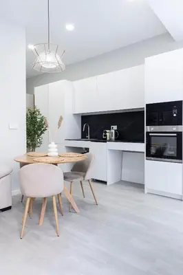a kitchen with white cabinets and a wooden table and chairs at Favara Suites B by Concept Flats in Valencia