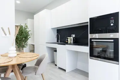 a white kitchen with a table and a microwave at Favara Suites B by Concept Flats in Valencia