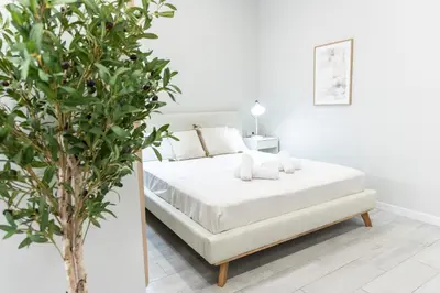 a white bedroom with a bed and a plant at Favara Suites B by Concept Flats in Valencia