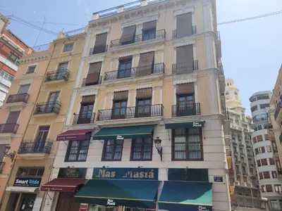 a tall yellow building with a sign on it at Living Valencia Apartments - Merced in Valencia