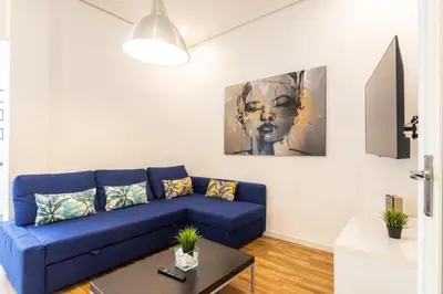 a living room with a blue couch and a painting at Mestalla Apartment Ideal for Mid-Term Stays in Valencia