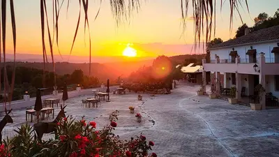 a sunset with birds in a courtyard with a building at Masia de Matuta in Vall de Almonacid