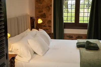a bedroom with a bed with white pillows and a window at Masia de Matuta in Vall de Almonacid