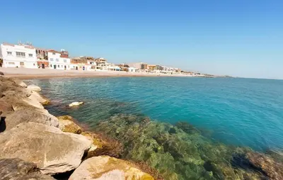 a beach with rocks and the ocean and buildings at 2 Bedroom Amazing Apartment In Moncofa in Moncófar