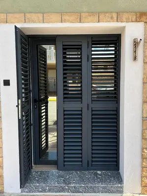 a door with black shutters on a building at El refugio del mar in Playa de Mar