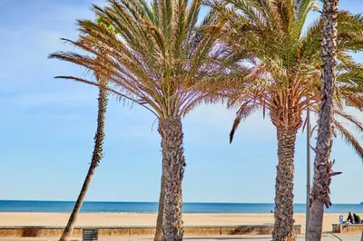 three palm trees on a beach near the ocean at ApartUP Patacona Sunrise Duplex II in Valencia