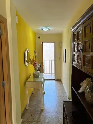 a hallway with yellow walls and a table with a mirror at Acogedor Apartamento Cullera 200 metros playa in Cullera