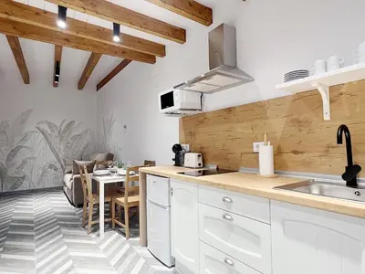a kitchen with white cabinets and a table in a room at Encantador apartamento vigas de madera in Valencia