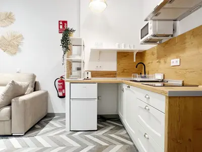a kitchen with white cabinets and a sink and a couch at Encantador apartamento vigas de madera in Valencia