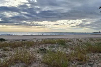 a beach with a person walking on the beach at Como en casa in Puerto de Sagunto