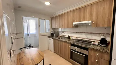 a kitchen with wooden cabinets and a wooden table at Vacaciones en el mar in Puerto de Sagunto