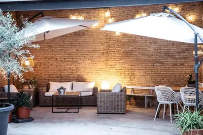 a patio with a couch and chairs and an umbrella at Tradicional Casa con patio Ruzafa in Valencia